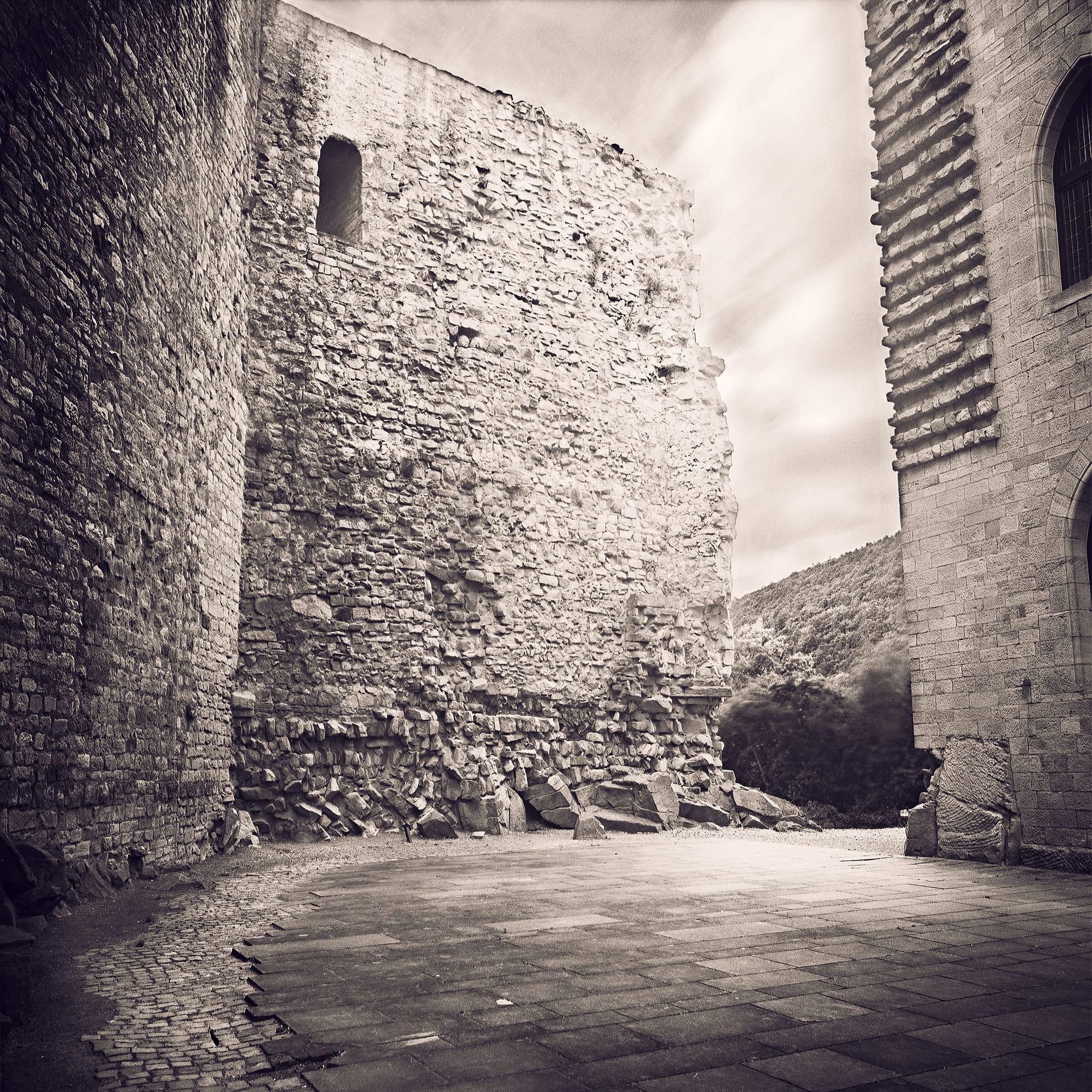 Ruined stone keep and rubble in an empty castle courtyard, cloud drawn out by a long exposure
